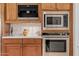 Modern kitchen appliances, including a built-in coffee maker, oven, and microwave, with wooden cabinetry at 10934 E La Verna Way, Scottsdale, AZ 85262