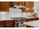 Stainless steel kitchen range with oven, complemented by white subway tile backsplash and wooden cabinets at 10934 E La Verna Way, Scottsdale, AZ 85262