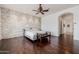 Spacious primary bedroom showcasing a stone accent wall, hardwood floors, and an open doorway to another room at 10934 E La Verna Way, Scottsdale, AZ 85262