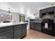 Updated kitchen featuring dark wood cabinets, modern appliances, sleek countertops, and an open-concept design to the living area at 10939 W Meadowbrook Ave, Phoenix, AZ 85037