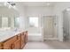 Bathroom showcasing double sinks, a bathtub, a walk-in shower with a glass door, and white walls at 11010 W Palm Ln, Avondale, AZ 85392