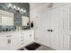 Modern bathroom featuring double sinks, white cabinetry, black hardware, and unique glass tile accent wall at 1144 W Tremaine Ave, Gilbert, AZ 85233
