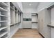 Spacious walk-in closet with custom shelving, cabinets, and wood flooring at 12225 E Cortez Dr, Scottsdale, AZ 85259