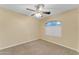 Inviting bedroom with carpet, ceiling fan and a window offering views, enhances the room's appeal at 14010 N 126Th Ave, El Mirage, AZ 85335