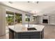 Modern kitchen island features sink, granite countertops, and scenic backyard views from the sliding glass door at 15010 W Hope Dr, Surprise, AZ 85379