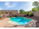 Inviting backyard pool with a unique shape, surrounded by desert landscaping and block fencing at 15010 W Hope Dr, Surprise, AZ 85379