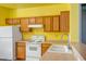Traditional kitchen with wood cabinets, light countertops and white appliances under yellow walls at 20007 N Organ Pipe Dr, Surprise, AZ 85374
