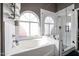 Bright bathroom featuring shower, tub, and beautiful arched windows for natural light at 238 W Marco Polo Rd, Phoenix, AZ 85027