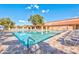 A spacious community pool with lounge chairs, tables and chairs, shaded area, and surrounding green trees at 2461 Leisure World --, Mesa, AZ 85206