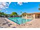 A spacious community pool with lounge chairs, blue umbrellas, tables and chairs, and surrounding green trees at 2461 Leisure World --, Mesa, AZ 85206