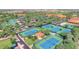 Beautiful aerial view featuring tennis and pickleball courts, lush desert landscaping, and community buildings at 2885 N 164Th Dr, Goodyear, AZ 85395