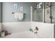 Bright white tiled bathtub shower combo with mounted toiletries and nautical art prints at 462 S Marie Dr, Chandler, AZ 85225