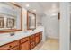 Bathroom with dual sinks, warm wood cabinets, large mirrors, and a decorative wall sconce at 5830 E Mckellips Rd # 30, Mesa, AZ 85215