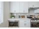 Kitchen featuring white cabinets, a stainless steel microwave, and a range hood with tile backsplash at 630 W Laredo St, Chandler, AZ 85225