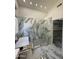Luxurious bathroom featuring marble walls, dual shower heads, and modern glass shower at 6821 W Donald Dr, Glendale, AZ 85310