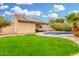 An expansive backyard shows a swimming pool, lush grass, a covered patio, and solar panels on the roof at 7229 S Butte Ave, Tempe, AZ 85283