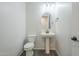 Cozy powder room with a pedestal sink, toilet, and neutral colors at 7531 W Odeum Ln, Phoenix, AZ 85043
