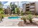 Community hot tub with lounge chairs, mature trees, desert landscaping, and nearby building at 7625 E Camelback Rd # B124, Scottsdale, AZ 85251