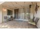 Relaxing covered patio with tile flooring, outdoor seating, and sliding glass doors with decorative shutters at 7625 E Camelback Rd # B124, Scottsdale, AZ 85251