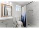Bathroom featuring a shower with white tile, toilet, vanity, and small window at 8044 N 10Th Pl, Phoenix, AZ 85020