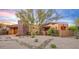 Inviting home with stone accents, desert landscaping, and sunset sky at 9998 E Taos Dr, Scottsdale, AZ 85262