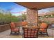 Relaxing covered patio with comfortable seating, complemented by a stone pillar and tranquil desert views at 9998 E Taos Dr, Scottsdale, AZ 85262