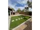 Landscaped backyard with an artificial lawn, stone patio, and beautiful palm trees at 3229 W Five Mile Peak Dr, San Tan Valley, AZ 85144