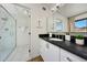 Bright bathroom featuring a glass shower and vanity with a black countertop and white cabinets at 5001 E Redfield Rd, Scottsdale, AZ 85254