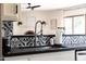 A modern kitchen features a stainless steel sink, black countertops and a backsplash with black-and-white patterned tiles at 5001 E Redfield Rd, Scottsdale, AZ 85254