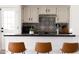 Modern kitchen featuring white cabinetry, black countertops, black and white backsplash, and counter seating at 5001 E Redfield Rd, Scottsdale, AZ 85254
