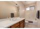 Neutral bathroom featuring a tub, window, oak vanity with a white sink, and large mirror at 6043 W Robin Ln, Glendale, AZ 85310
