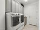 Well-lit laundry room with gray cabinets, washer, and dryer at 11366 E White Feather Ln, Scottsdale, AZ 85262