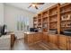 Bright office with custom built-ins, wood floors and shuttered window offers a perfect workspace at 11366 E White Feather Ln, Scottsdale, AZ 85262