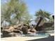 Backyard pool featuring a rock waterfall, palm trees, and lush landscaping at 14253 N Honeysuckle N Dr, Fountain Hills, AZ 85268