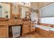 Well-lit bathroom featuring double sinks, stone tile accents and a soaking tub at 1437 E Glenhaven Dr, Phoenix, AZ 85048