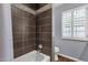 Modern bathroom featuring a tiled shower, bathtub with modern fixtures, and a window with white shutters at 1978 E Carver Rd, Tempe, AZ 85284