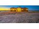 Inviting exterior of a single-story home featuring warm lighting and a spacious front yard with desert landscaping at 3033 N 367Th Ave, Tonopah, AZ 85354