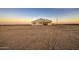 A single story home's exterior is bright and features a covered patio, enhanced by the sunset glow at 3033 N 367Th Ave, Tonopah, AZ 85354