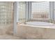 Bright bathroom featuring a soaking tub with glass block window and a luxurious glass block shower enclosure at 3931 E Fox Cir, Mesa, AZ 85205