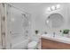 Clean bathroom with a wood vanity, round mirror, and a tub-shower combo with floral curtains at 5315 S River Dr, Tempe, AZ 85283