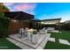 Charming backyard with a stone fire pit, lush landscaping, and a covered pergola, perfect for outdoor entertaining at 10741 E Palladium Dr, Mesa, AZ 85212