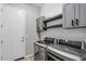 Well-lit laundry room with stainless steel washer and dryer, gray cabinets and shelves, and shiplap accent wall at 10741 E Palladium Dr, Mesa, AZ 85212
