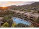 A desert community with townhouses surrounds a pool and patio area, all beneath a sunset-painted sky and mountain backdrop at 13450 E Via Linda -- # 2041, Scottsdale, AZ 85259