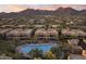 Overhead view of desert community townhouses with a pool at its center, set against a backdrop of mountains and sunset hues at 13450 E Via Linda -- # 2041, Scottsdale, AZ 85259