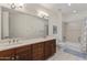 Bright bathroom featuring double sinks, wood cabinetry, a large mirror, and a shower over tub at 13450 E Via Linda -- # 2041, Scottsdale, AZ 85259
