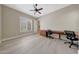 Bright bedroom with a ceiling fan, light hardwood floors, and a built-in desk area at 28770 N 69Th Ln, Peoria, AZ 85383