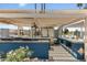 A community outdoor kitchen with a grill, refrigerator, counter space, fan and shaded pergola structure at 6942 S Championship Dr, Chandler, AZ 85249