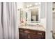 Bathroom featuring a vanity with granite countertop, decorative mirror, and modern lighting at 10407 W Reade Ave, Glendale, AZ 85307