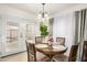 Cozy dining room features a wooden table, four chairs, elegant light fixture, and natural light from the glass patio doors at 10407 W Reade Ave, Glendale, AZ 85307