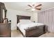 Comfortable main bedroom with a dark wood frame bed, ceiling fan, and neutral colored walls at 10407 W Reade Ave, Glendale, AZ 85307